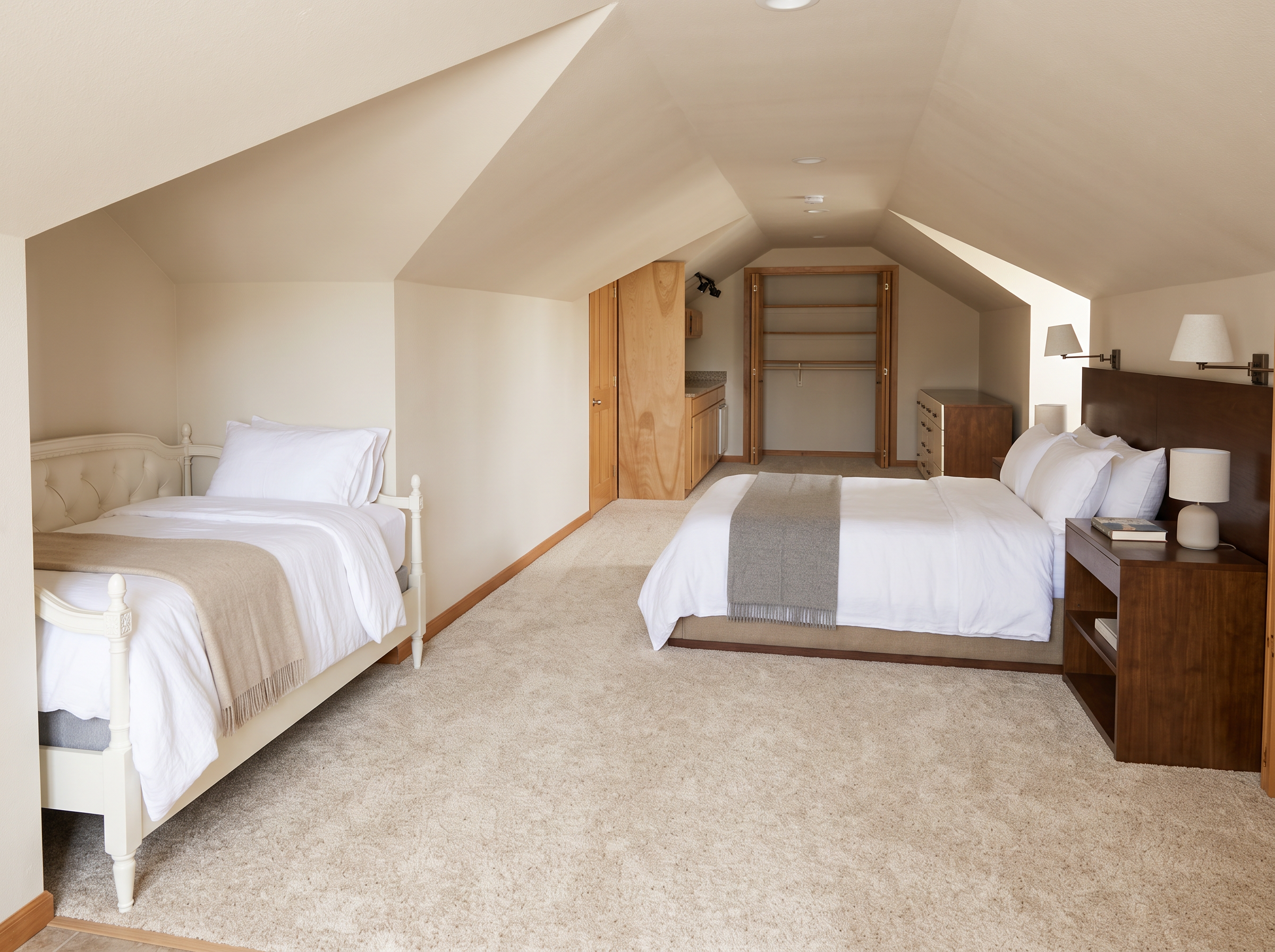The apartment loft bedroom under a vaulted ceiling in white linen
