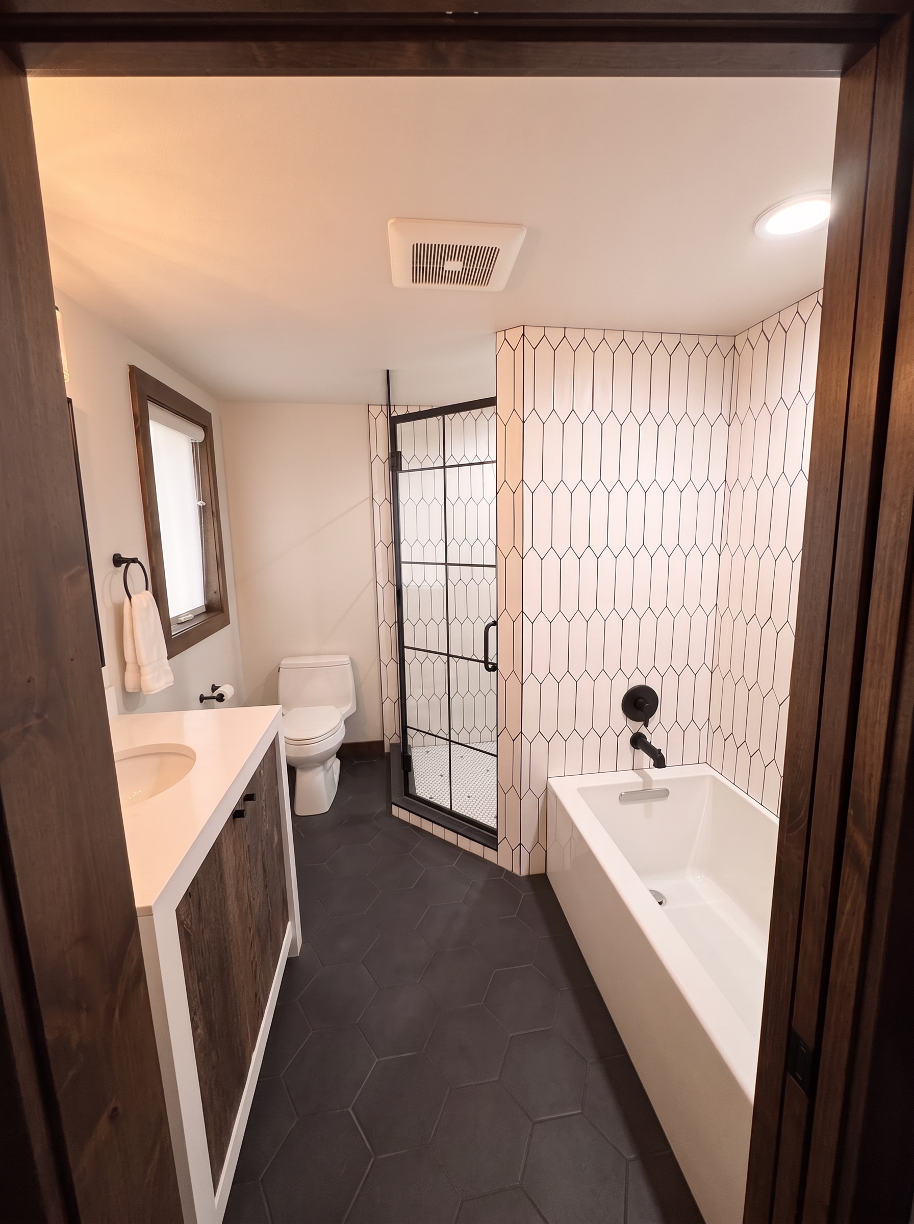 A guest bath with white picket tile, soaking tub, and daylight