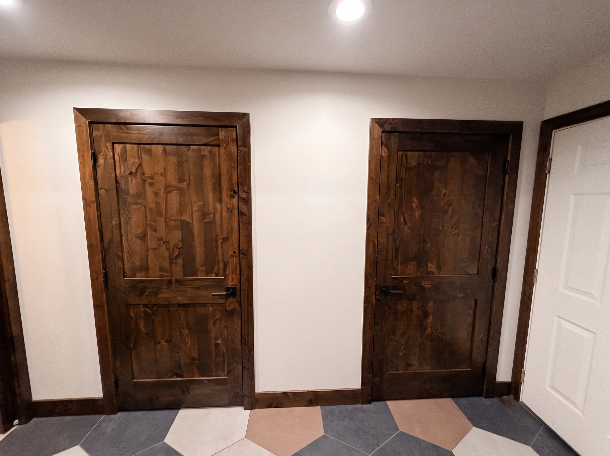 A hallway with hexagonal tile floor and a door to the outside