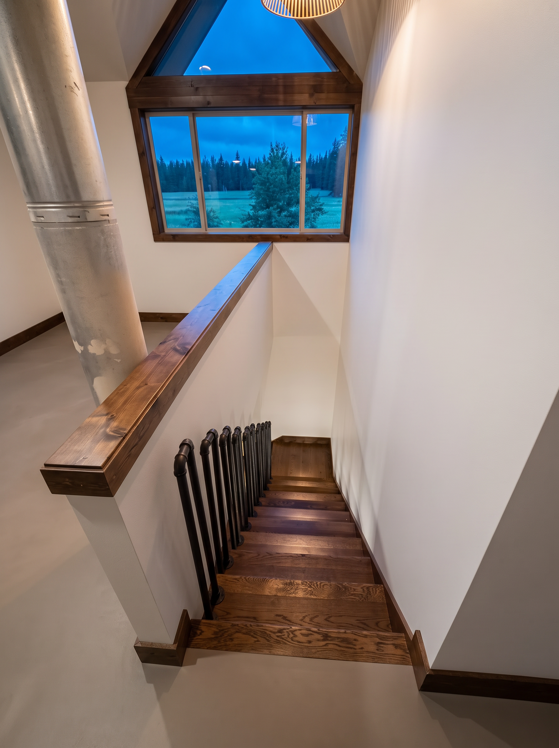 The stair landing at dusk, looking down into the main home