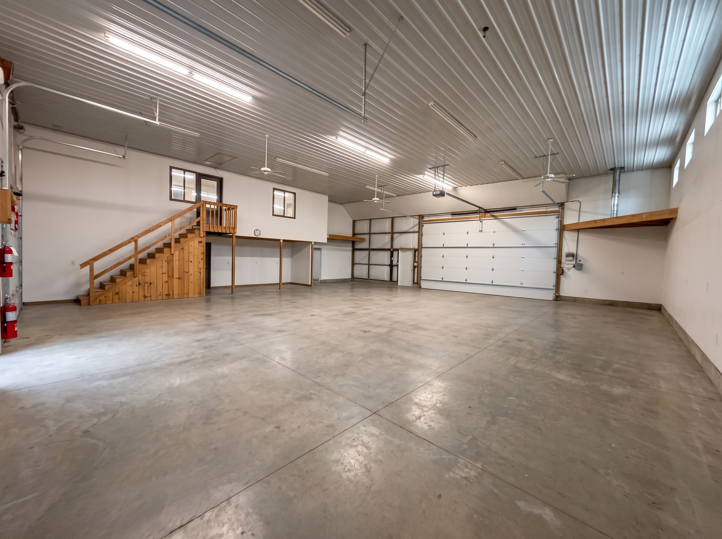 The workshop interior, an open concrete floor beneath timber rafters